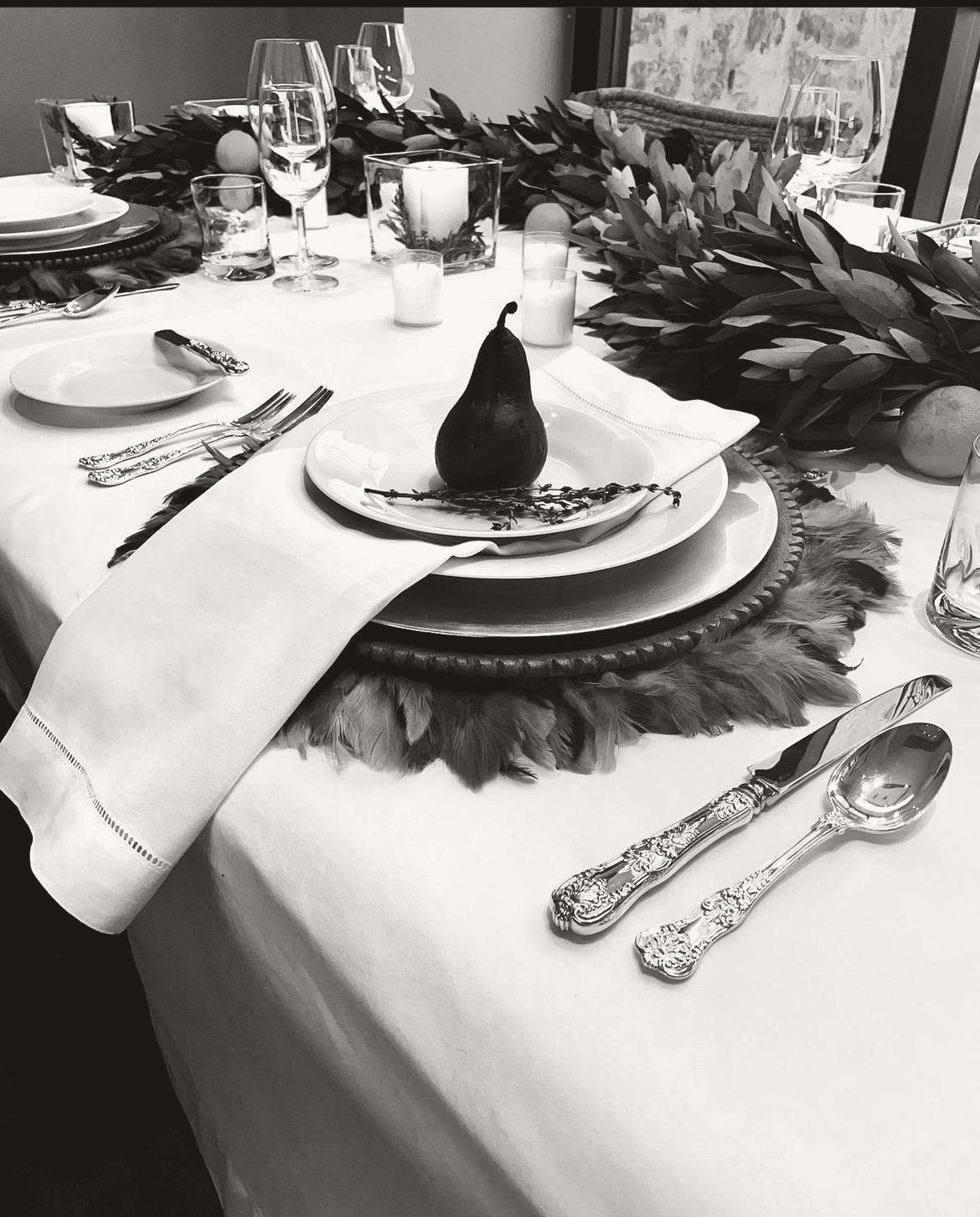 A formal table setting in a private estate, fine china, polished silver, and a poached pear